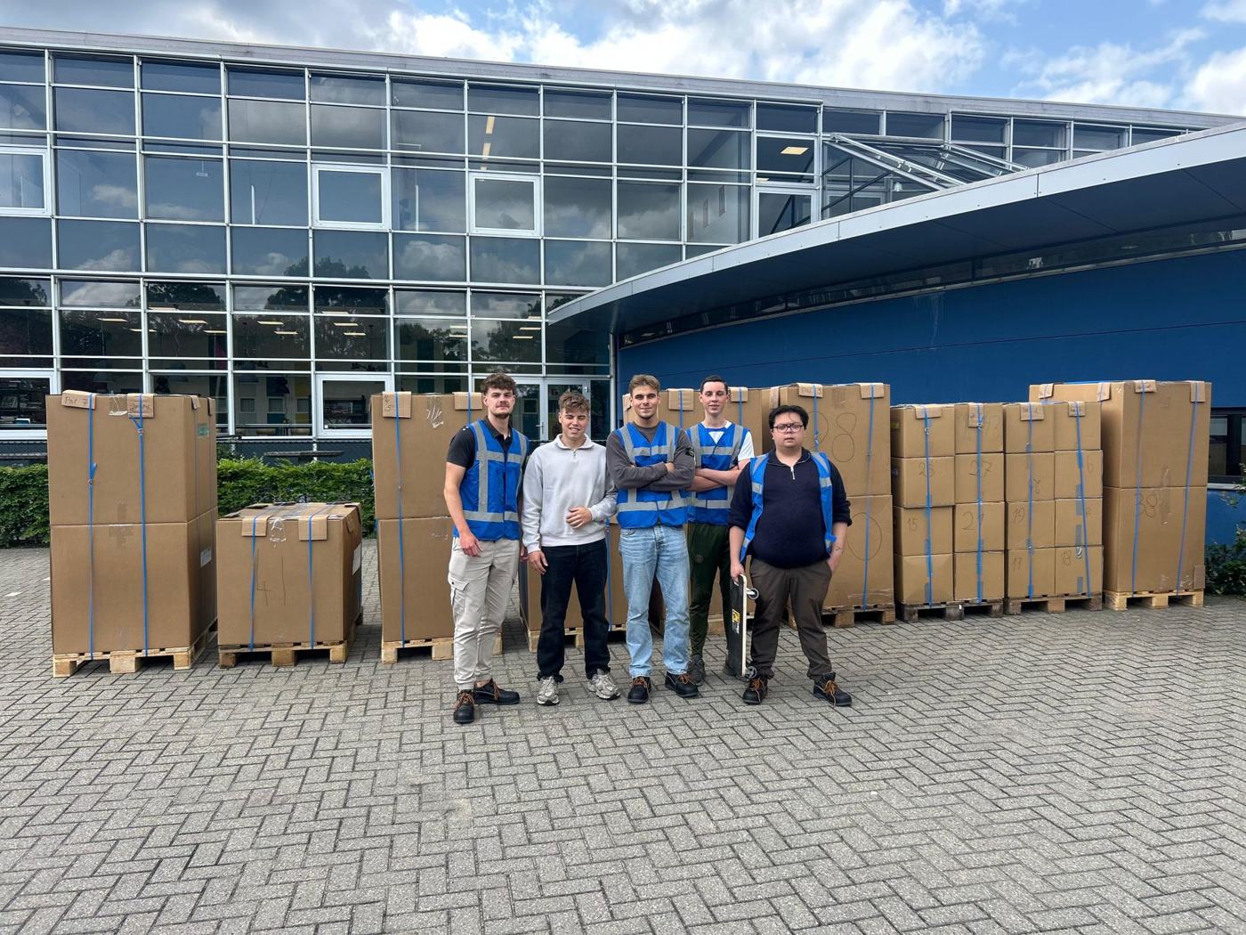 Studenten naast pallets met dozen voor de container in 2024