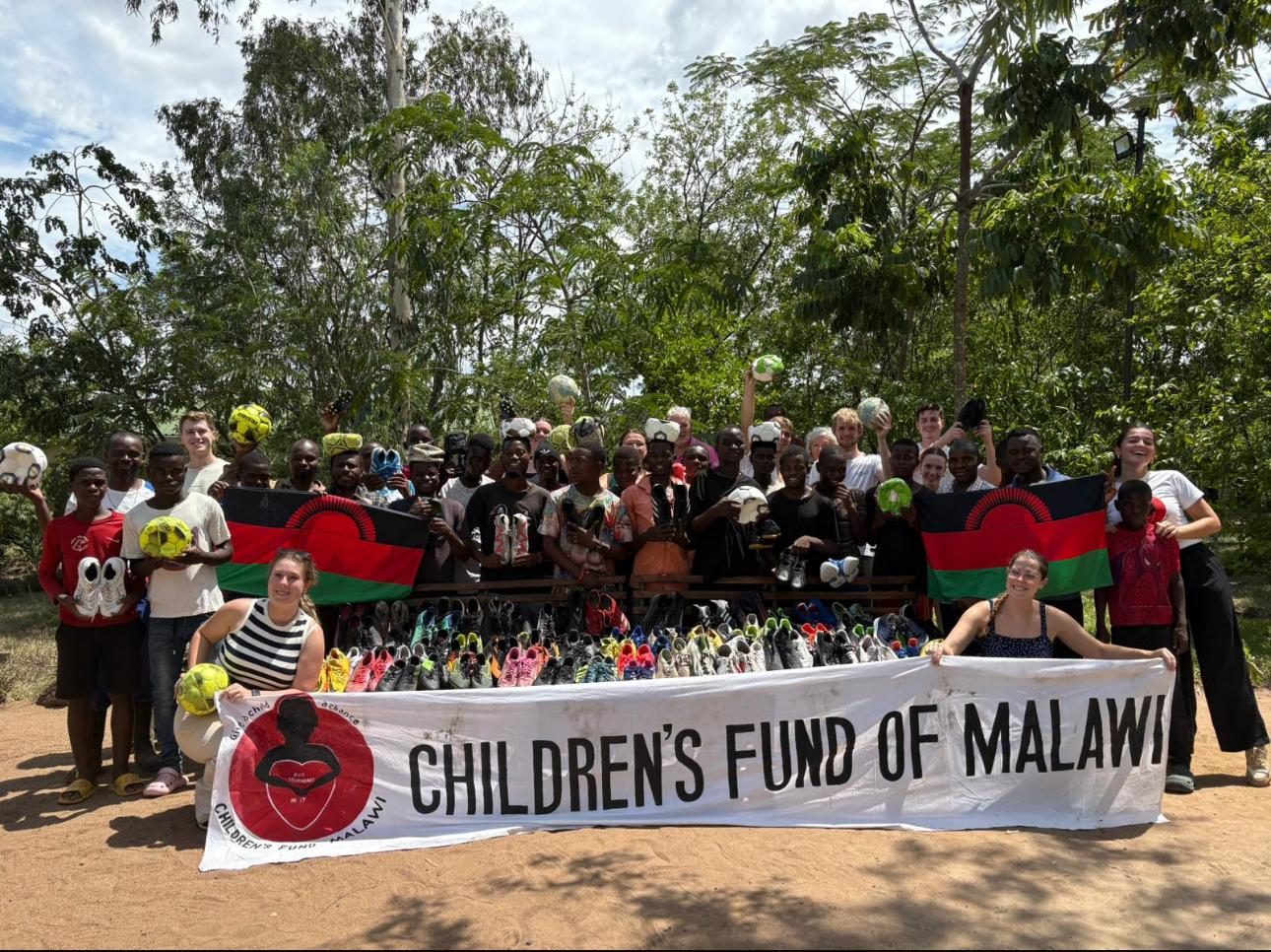 De groep van 2024 met jongeren van Green Malata achter een spandoek van Children's Fund of Malawi